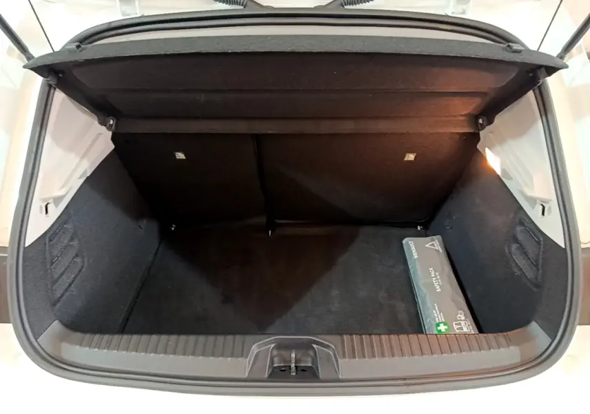 Coffre ouvert vu de l'arrière d'une Renault Clio blanche 2021, avec un kit de sécurité posé à droite.