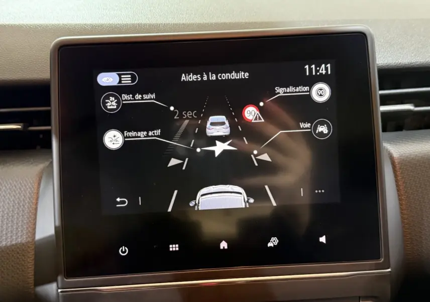 Écran tactile central de la Renault Clio Business blanc, affichant les aides à la conduite avec alertes et distances.
