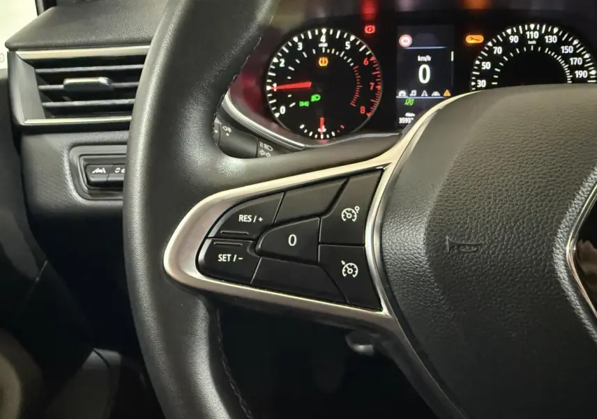 Détail intérieur montrant le volant multifonctions en cuir synthétique et la commande d'assistance au freinage d'urgence côté gauche.