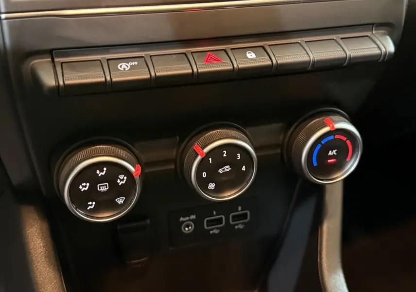 Gros plan sur les commandes de climatisation et boutons de fonction du tableau de bord de la Renault Clio Business blanche de 2020.