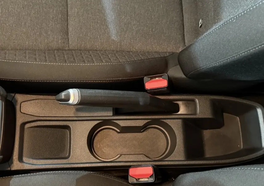 Gros plan sur la console centrale noire de la Renault Clio Business 2020, avec frein à main manuel et porte-gobelets.