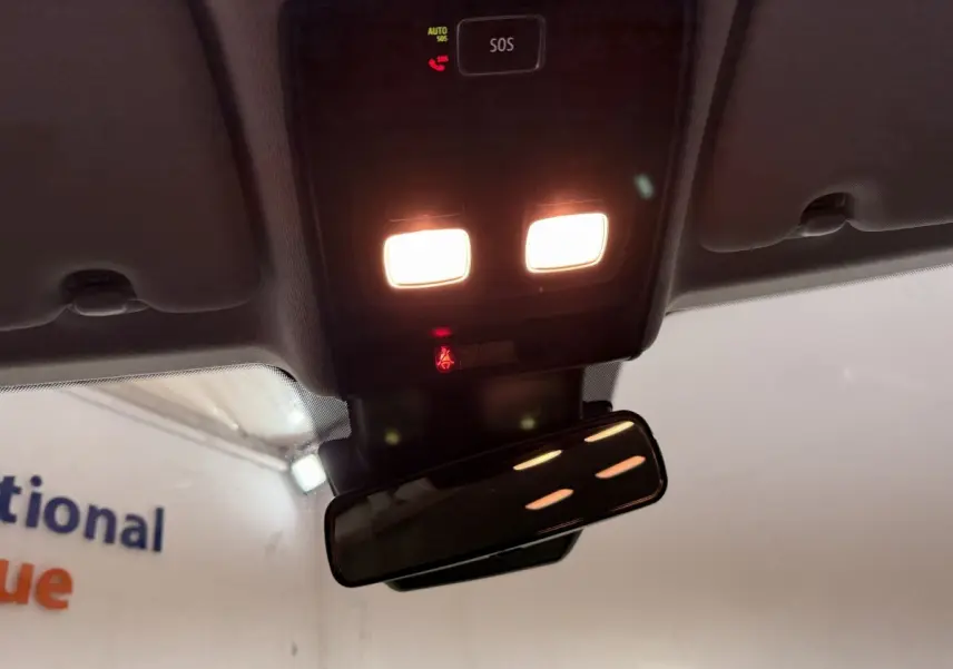 Vue intérieure en plongée du plafonnier allumé avec bouton SOS et rétroviseur intérieur d'une Renault Clio blanche.