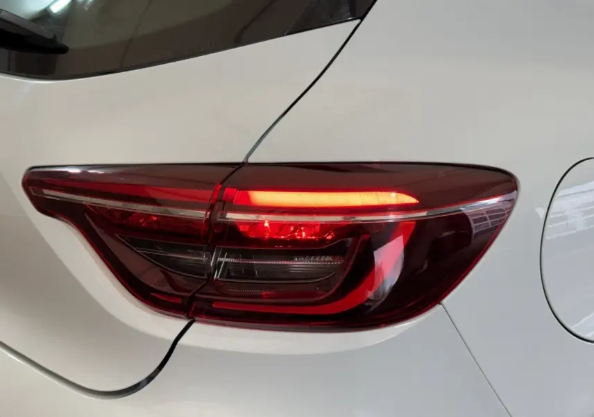 Gros plan sur le feu arrière droit rouge d'une Renault Clio Business blanche, avec la carrosserie visible autour.