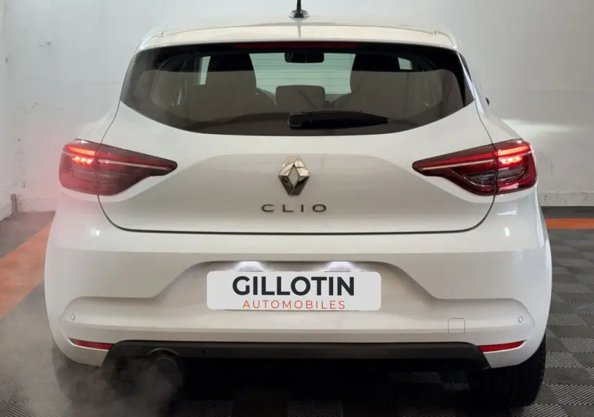 Vue arrière d'une Renault Clio Business blanche de 2020 avec feux arrière allumés et logo centré.