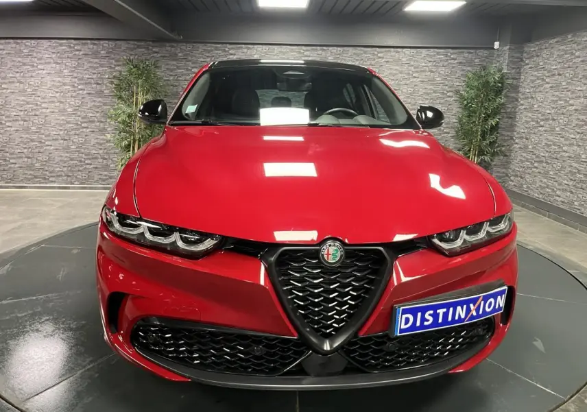 Vue frontale d'une Alfa Romeo Tonale rouge avec calandre noire et logo Alfa Romeo au centre.