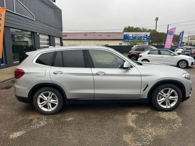 Vue de profil côté gauche d'un BMW X3 xDrive30eA 2020 en Glacier Silver avec jantes alliage 5 branches.