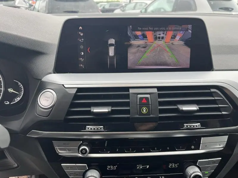 Vue intérieure du tableau de bord de BMW X3 xDrive30e 2020, écran de caméra de recul affiché, finition noire et argentée.