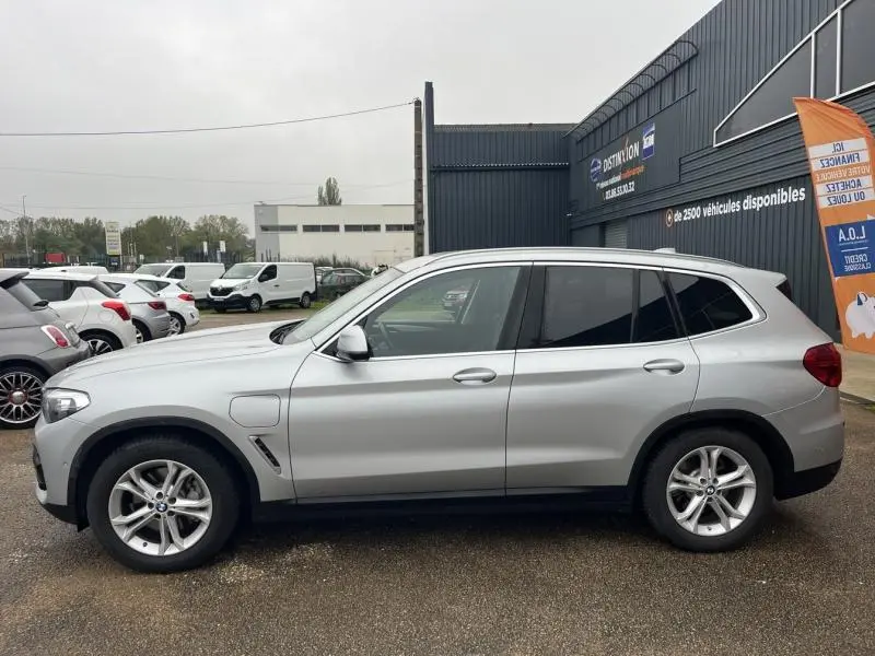 Vue de profil côté gauche d'un BMW X3 xDrive30eA 2020 hybride rechargeable en Glacier Silver avec jantes alliage 18 pouces.