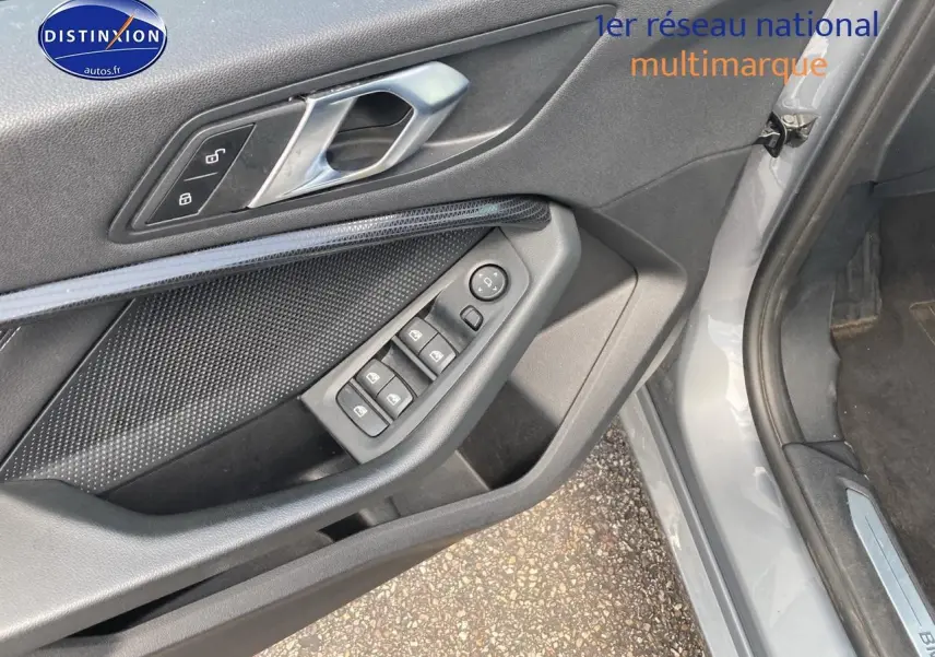 Vue rapprochée de la porte avant gauche grise foncée de la BMW Série 1 (f40) avec commandes de vitres et poignée métallique.