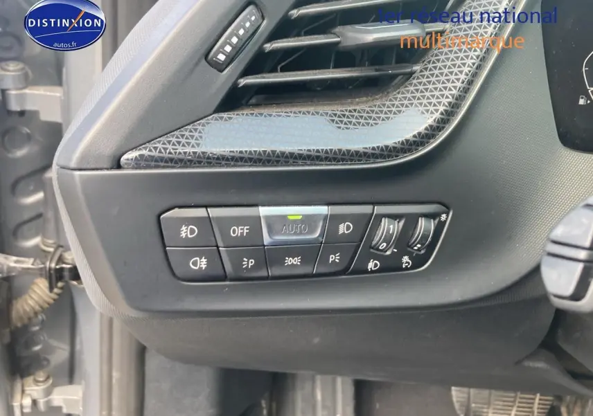 Détail des commandes d'éclairage sur la gauche du tableau de bord d'une BMW Série 1 gris foncé 2023.