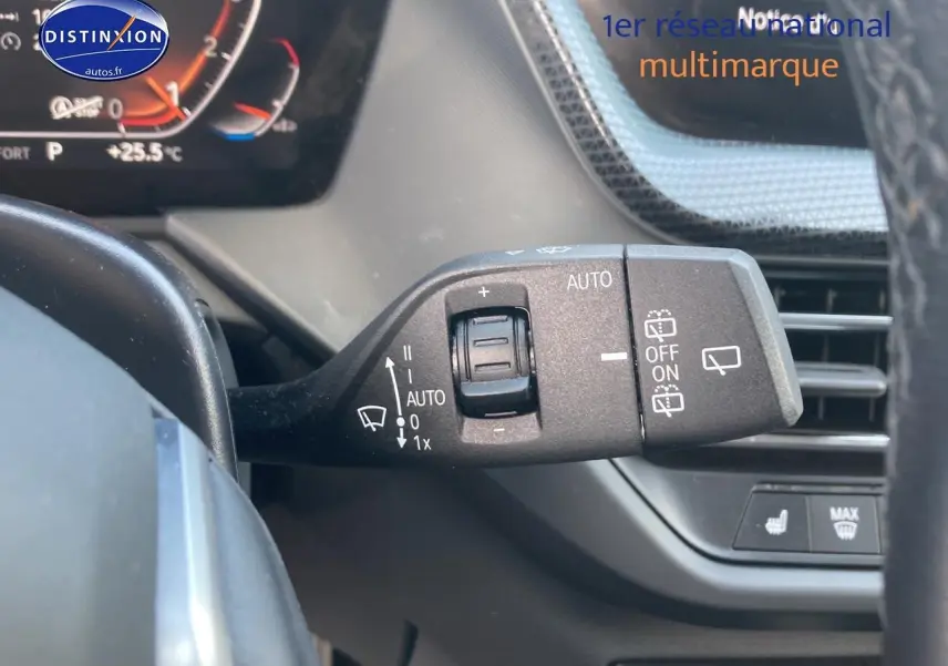 Gros plan sur la commande des essuie-glaces à gauche du volant dans l’habitacle gris foncé d’une BMW Série 1 118i 2023.