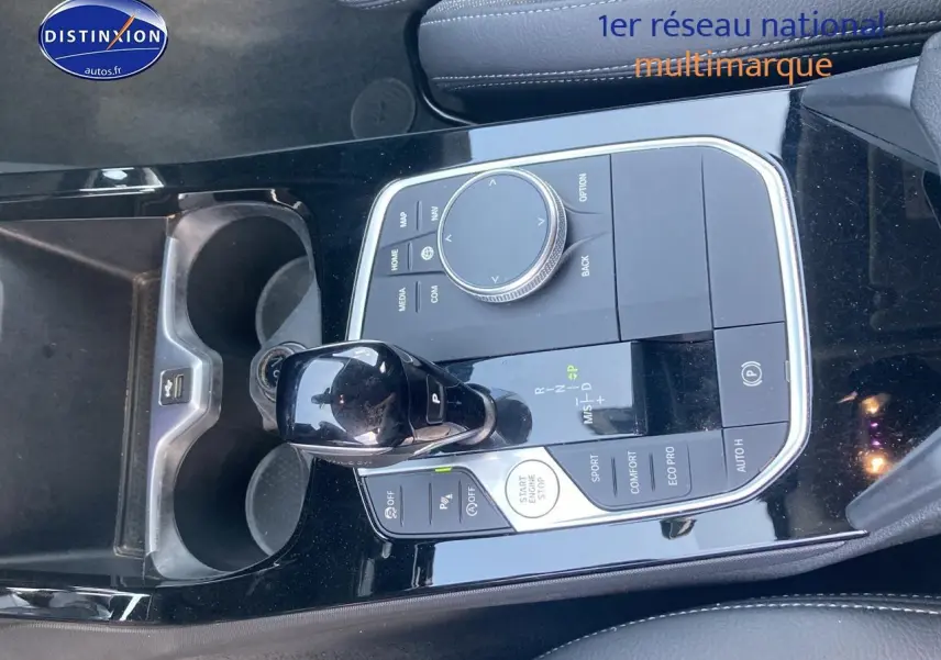 Gros plan sur la console centrale noire brillante de la BMW Série 1 118i 2023 avec levier de vitesse et commandes.
