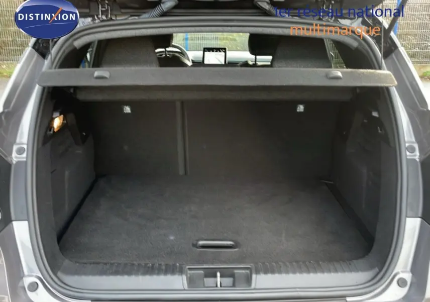 Vue arrière du coffre ouvert du Renault Captur gris Cassiopée métal avec toit noir, montrant un espace de rangement vide et propre.