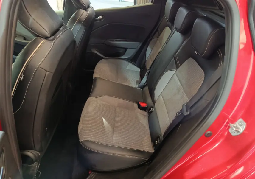 Vue intérieure arrière côté droit de la Renault Clio Techno TCe 90 rouge, sièges bicolores tissu et cuir avec surpiqûres blanches.