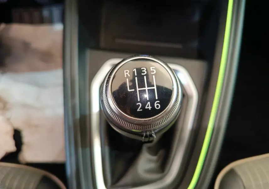 Gros plan sur le levier de vitesses manuel noir de la Renault Clio Techno TCe 90, entouré de garniture grise et éclairage vert.