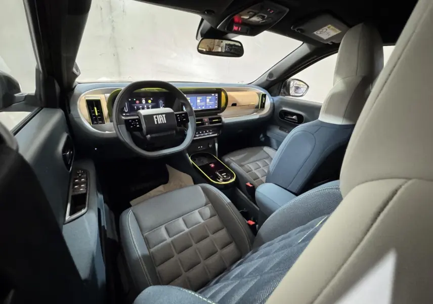 Vue intérieure avant droite de la Fiat Grande Panda marron 2025, tableau de bord moderne avec écran tactile et volant cuir.