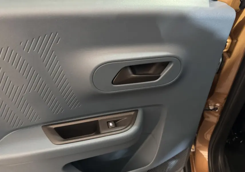 Vue rapprochée de la porte intérieure côté droit de la Fiat Grande Panda marron avec poignée et bouton de verrouillage.