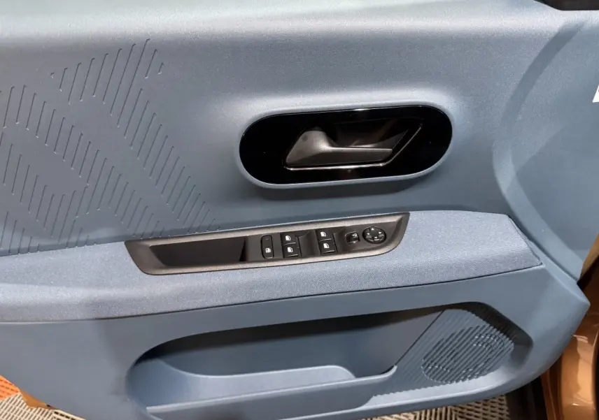 Gros plan sur la porte avant gauche marron de la Fiat Grande Panda 2025 avec commandes électriques et poignée noire.