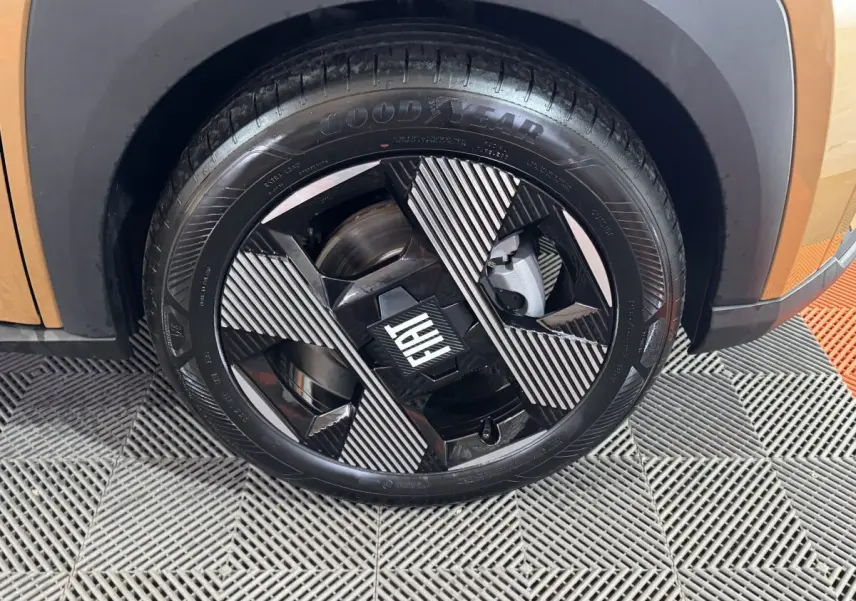 Gros plan sur la roue avant droite marron de la FIAT Grande Panda 1.2 Hybrid avec jante noire et motifs rayés.