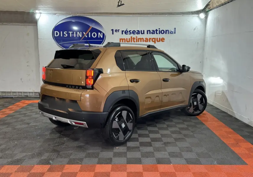 Vue 3/4 arrière droite d'une FIAT Grande Panda marron avec jantes noires et détails noirs contrastants dans un garage.