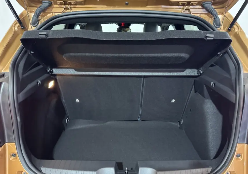 Coffre ouvert vu de l'arrière d'une FIAT Grande Panda marron 2025, intérieur noir et banquette arrière visible.