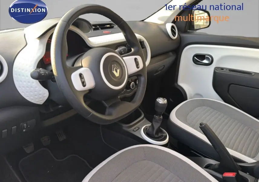Vue intérieure côté conducteur de la Renault Twingo gris acier 2021, volant multifonction et sièges tissu gris.