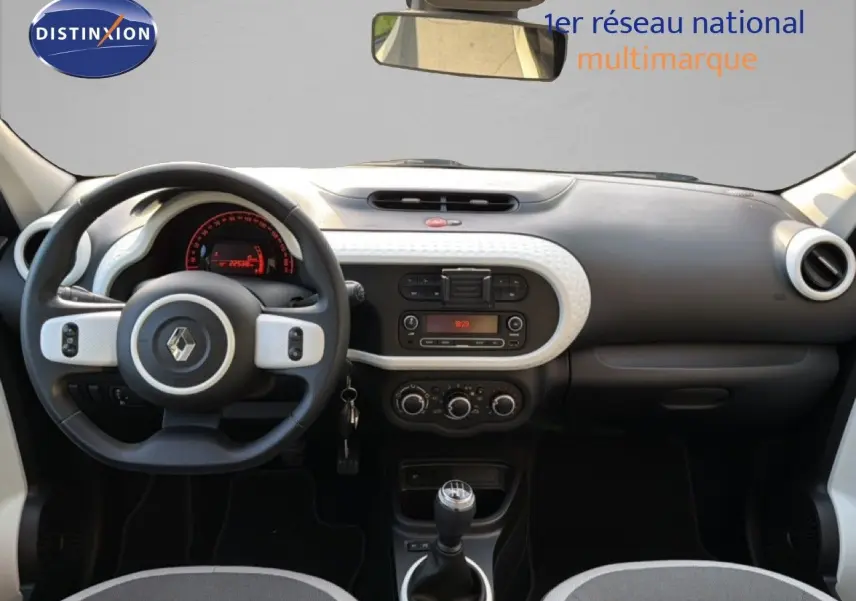 Vue intérieure avant du tableau de bord gris et noir de la Renault Twingo 1.0 SCE 65 Zen avec volant multifonction et levier de vitesse manuel.