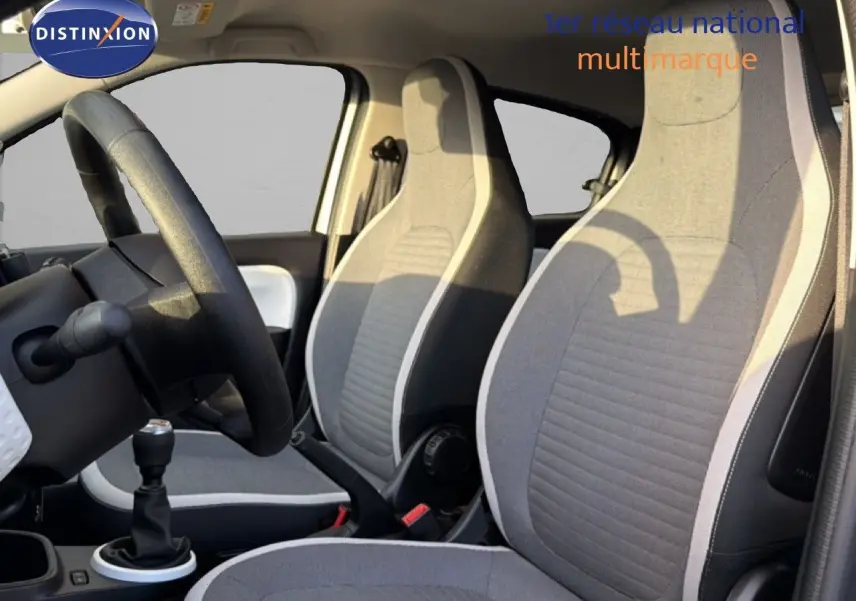 Vue intérieure côté conducteur de la Renault Twingo gris acier 2021, sièges tissu gris avec surpiqûres claires.