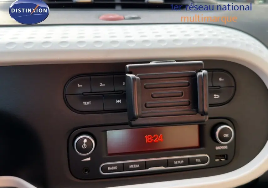 Gros plan sur la console centrale de la Renault Twingo gris acier 2021, affichant l’horloge digitale et commandes audio.