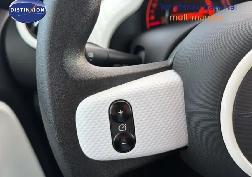 Gros plan sur les commandes de régulateur de vitesse sur le volant noir et gris acier d’une Renault Twingo 1.0 SCE 65 Zen.