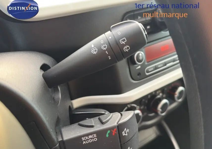 Gros plan sur les commandes au volant et la manette d’essuie-glace du tableau de bord d’une Renault Twingo gris acier.