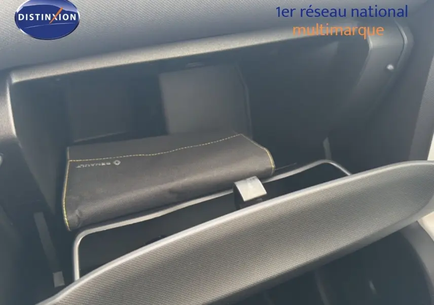 Vue intérieure du vide-poche côté passager d'une Renault Twingo gris acier, avec pochette Renault visible.