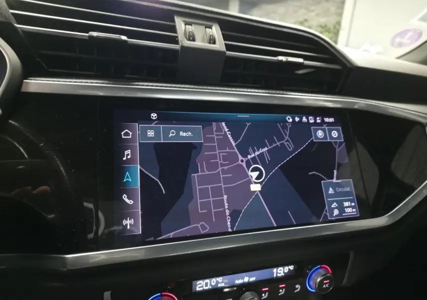 Écran tactile central affichant la navigation dans l’Audi Q3 S Line, intérieur noir avec commandes climatisation digitales.