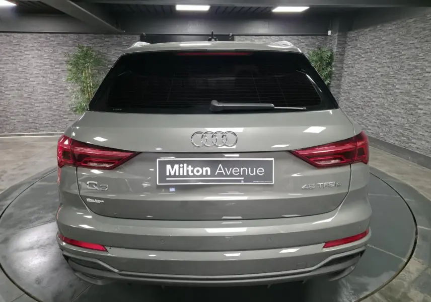 Vue arrière d'un Audi Q3 gris hybride rechargeable 45 TFSI e avec feux LED et vitres arrière surteintées.