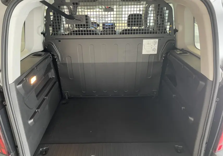 Vue arrière ouverte du Peugeot Rifter gris Artense, montrant l'espace de chargement avec cloison métallique de séparation.