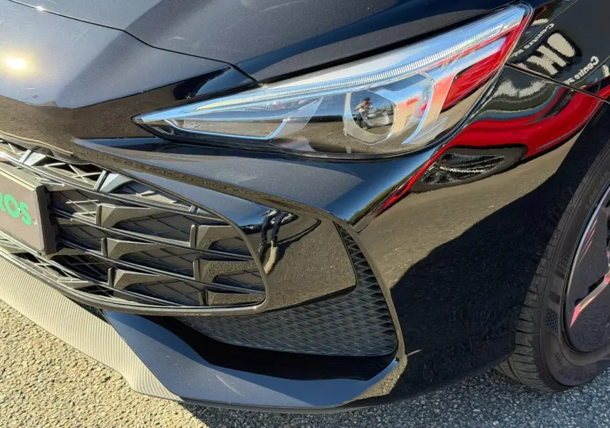 Gros plan sur l'avant droit du MG3 1.5 Hybrid+ 2024 en Pebble Black métallisé, mettant en valeur le phare et la calandre.