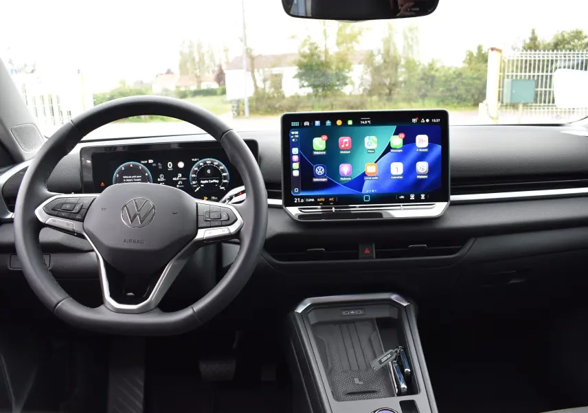 Vue intérieure du tableau de bord du Volkswagen T-Roc blanc 2025, avec écran tactile central et volant multifonction.