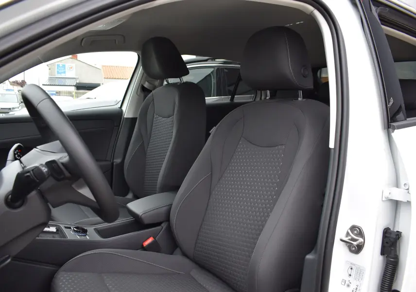 Vue intérieure côté conducteur du Volkswagen T-Roc blanc 2025, sièges tissu gris avec coutures contrastées.