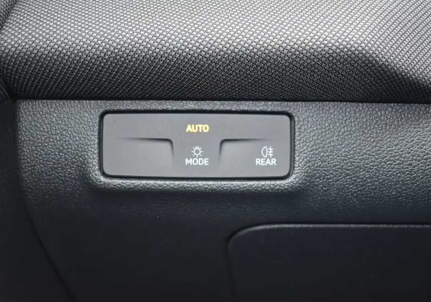 Détail du tableau de bord noir avec commande d'éclairage automatique et feux arrière sur Volkswagen T-Roc blanc.