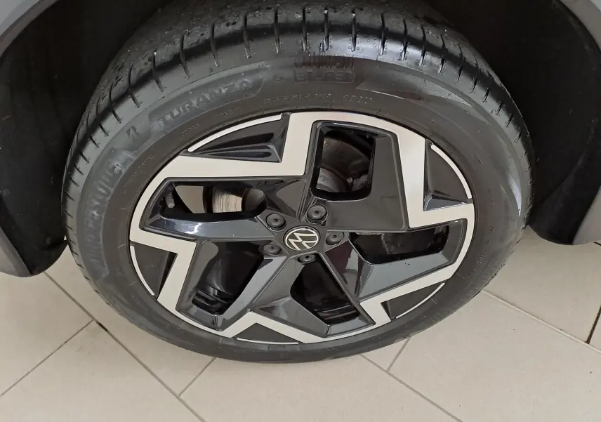 Gros plan sur la jante noire et argentée du Volkswagen Tiguan 2025, mettant en valeur le logo VW central.