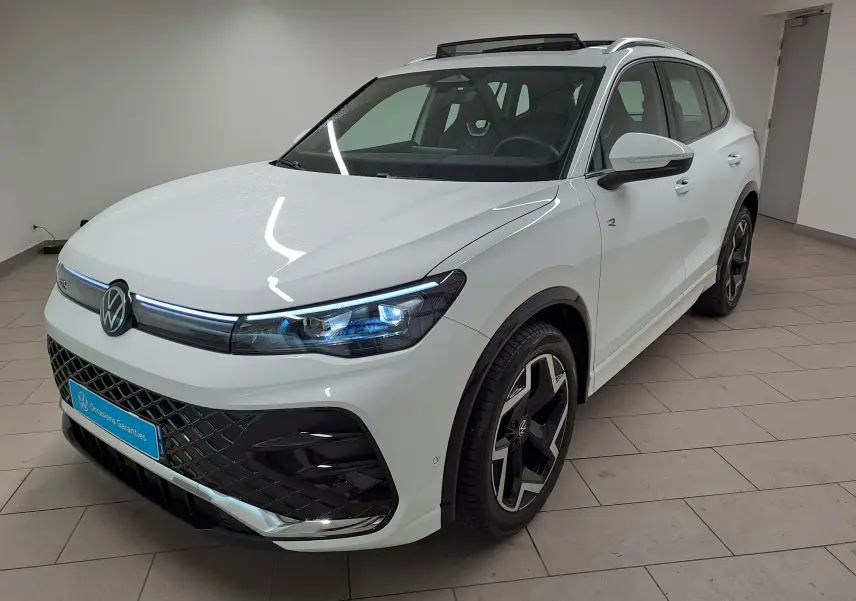 Vue 3/4 avant droite du Volkswagen Tiguan blanc pur 2025, finition R-Line avec jantes noires distinctives.