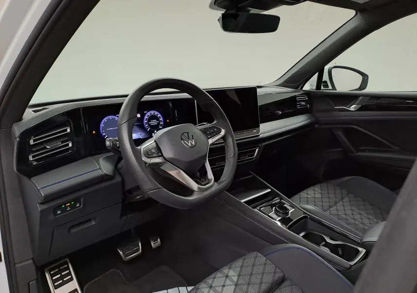 Vue intérieure côté conducteur du Volkswagen Tiguan 2025, tableau de bord moderne avec écran digital et finitions noires élégantes.