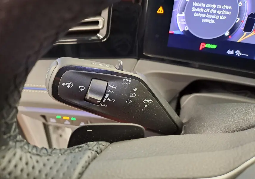 Gros plan sur la manette de commande des essuie-glaces du Volkswagen Tiguan blanc, avec tableau de bord numérique en arrière-plan.