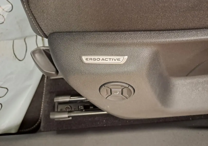 Détail du réglage de siège Ergo Active en plastique noir dans l'habitacle du Volkswagen Tiguan blanc.