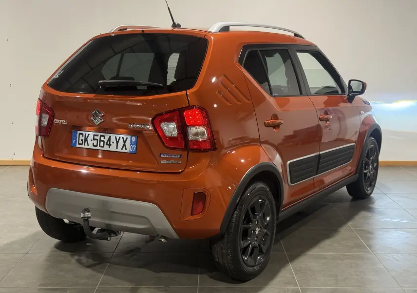 Vue 3/4 arrière droite d’un Suzuki Ignis orange 2022 avec barres de toit argentées et jantes noires.