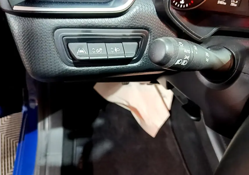 Vue intérieure côté gauche du tableau de bord bleu de la Renault Clio 2022 avec commandes d'assistance et commodo des phares.