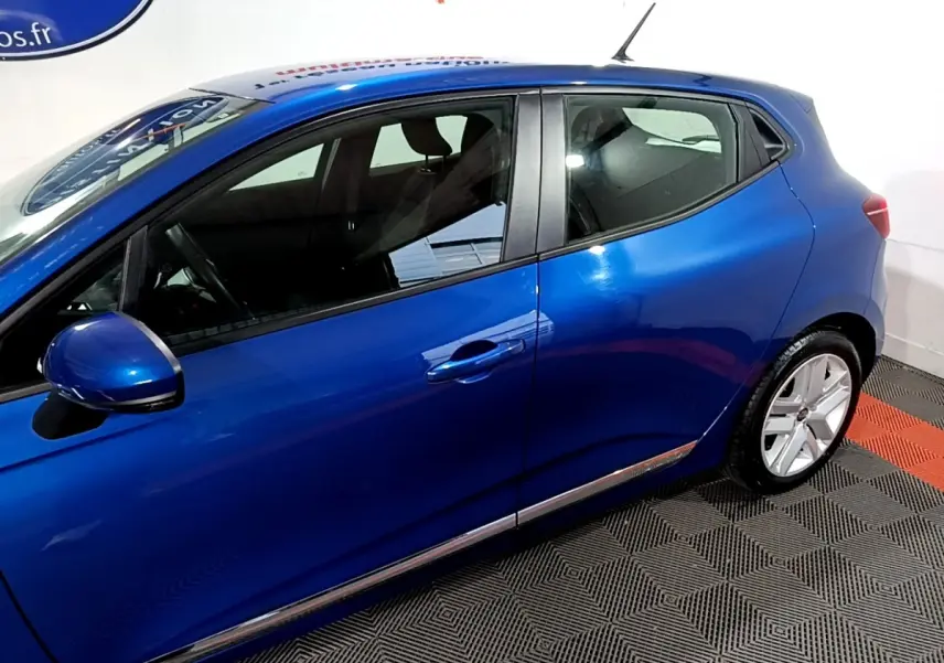 Vue latérale côté gauche d'une Renault Clio Business bleu métallisé, mettant en valeur la ligne fluide et les jantes alliage.