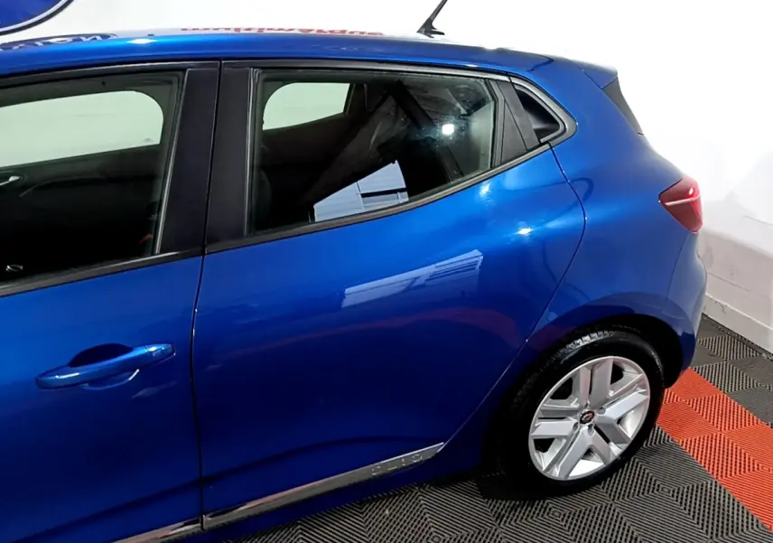 Vue côté gauche arrière d'une Renault Clio Business bleu métallisé avec jantes alliage et poignées de porte intégrées.