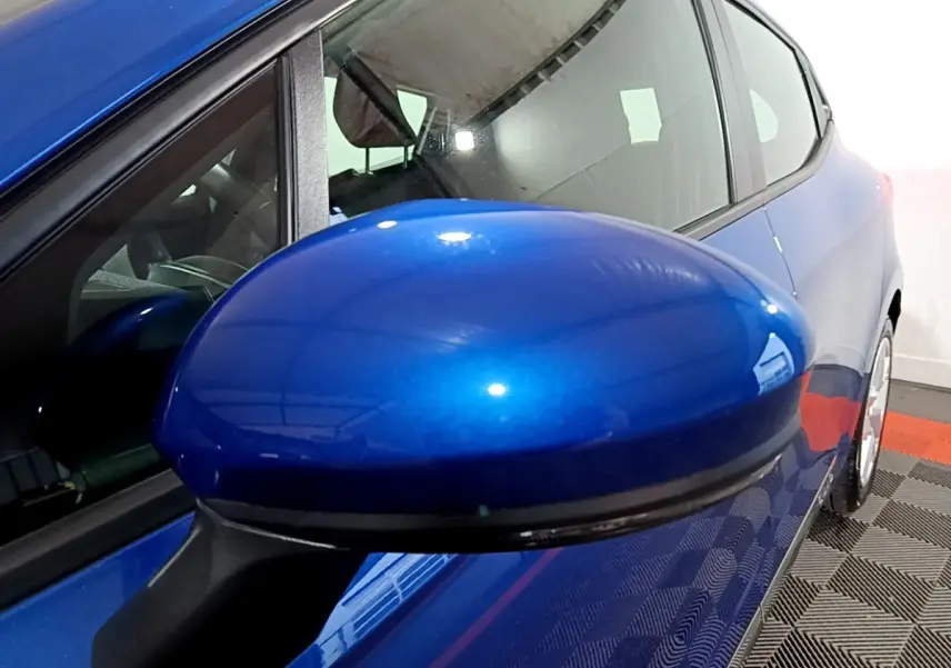 Rétroviseur bleu en gros plan côté gauche sur Renault Clio Business 2022, vue latérale partielle du véhicule.