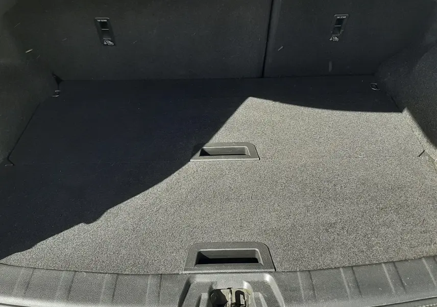 Coffre ouvert vu de face, espace de chargement vide avec tapis gris foncé, intérieur du Nissan Qashqai 2018.